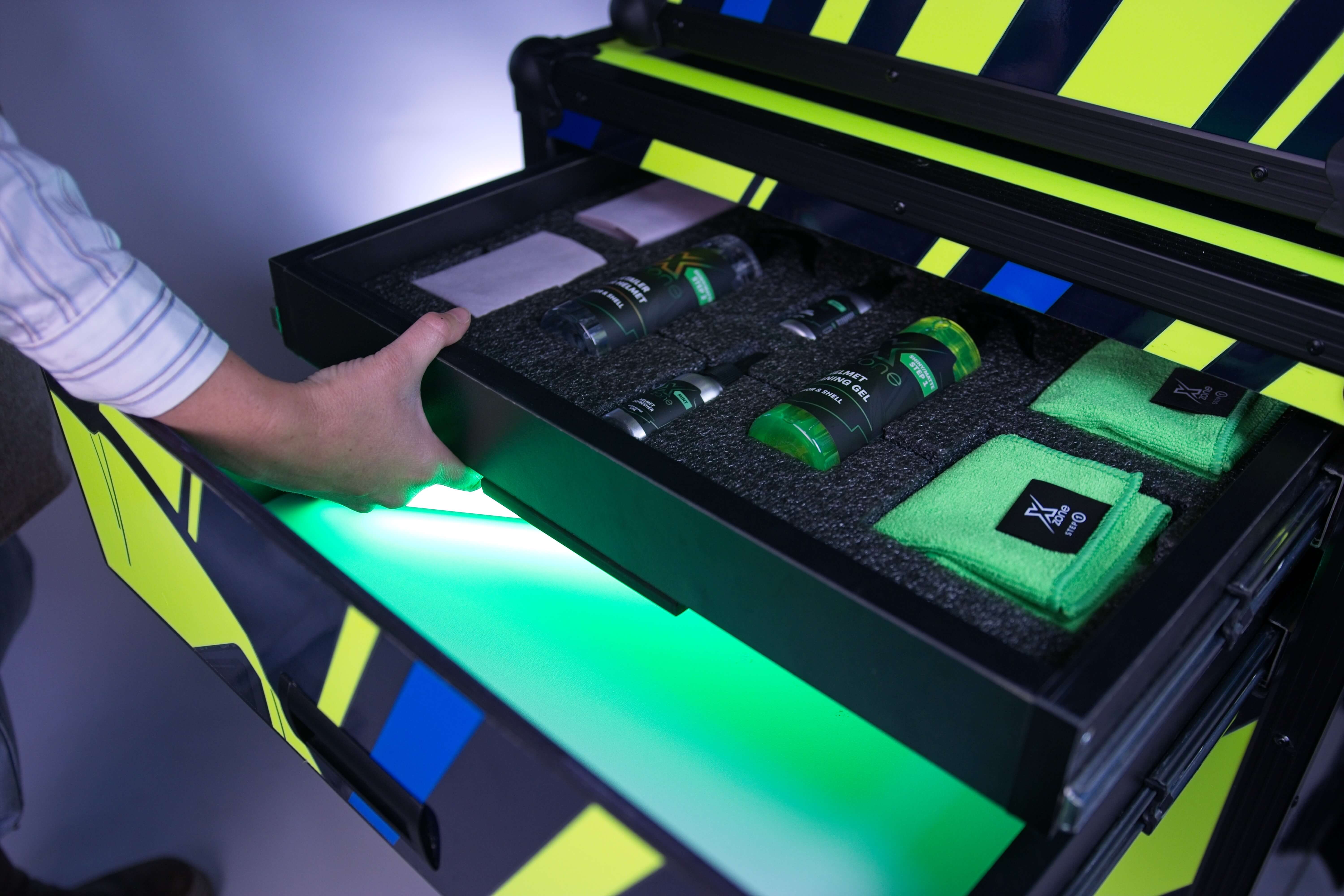 Zestaw Xzone Helmet Care w szufladzie kabiny do ozonowania – żel czyszczący, detailer i mikrofibry.