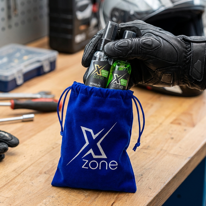 Zestaw Xzone w niebieskim woreczku na stole warsztatowym – kosmetyki do pielęgnacji odzieży motocyklowej