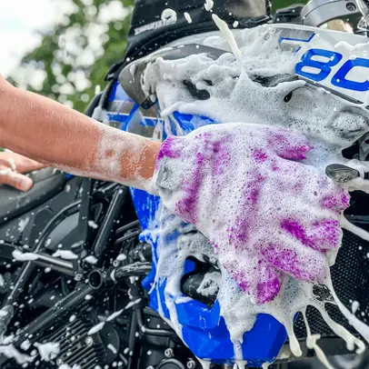 Rękawica z pianą myje motocykl Xzone — intensywna piana na niebieskim motocyklu