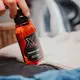 Butelka Xzone Merino Care – płyn do prania odzieży z wełny merino, trzymana w dłoni obok swetra.